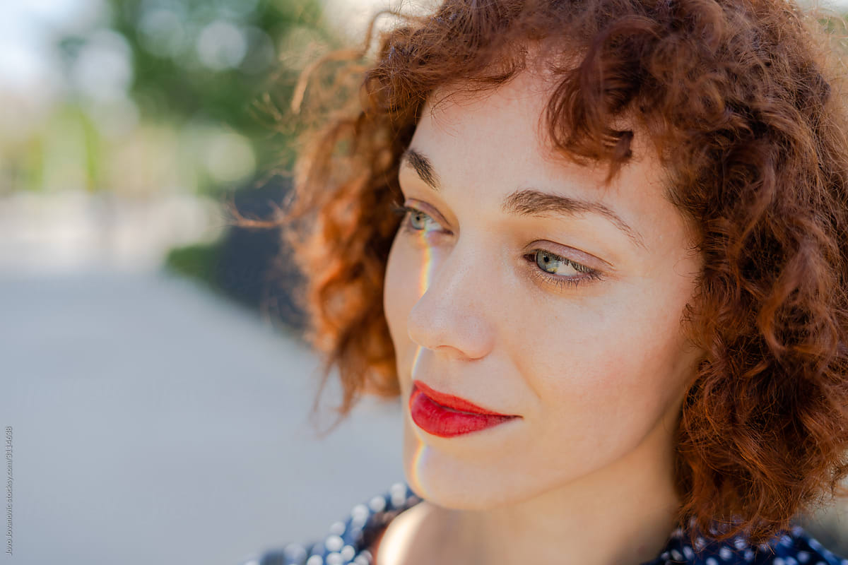 Close up of red haired woman with fair skin with rainbow light