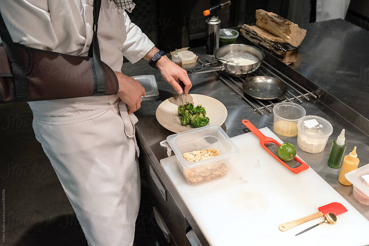 Chef with broken arm serving greens on plate