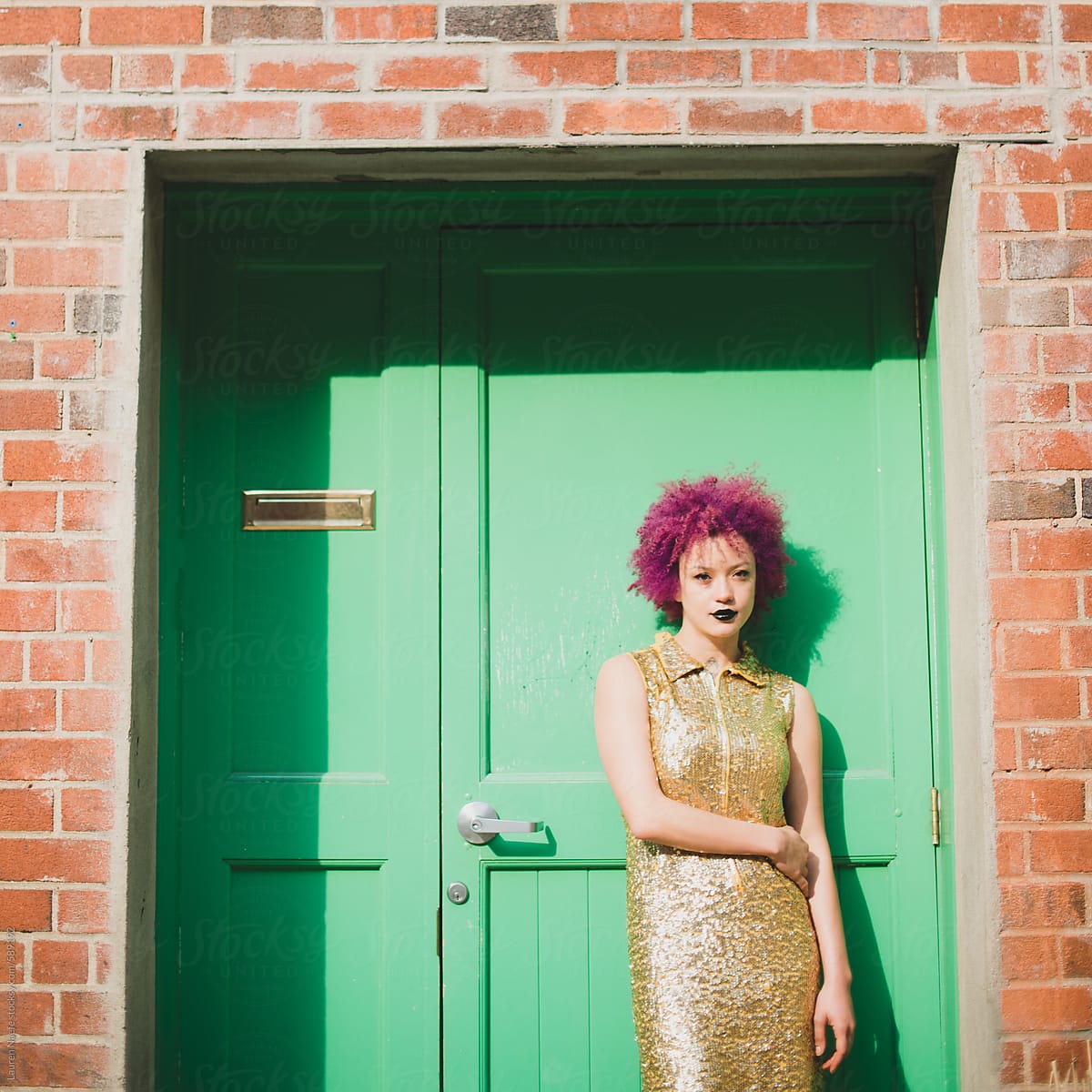 Young woman dressed up, standing against green door