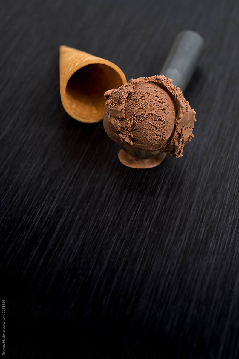 Scoop of chocolate ice cream and waffle cone on black background