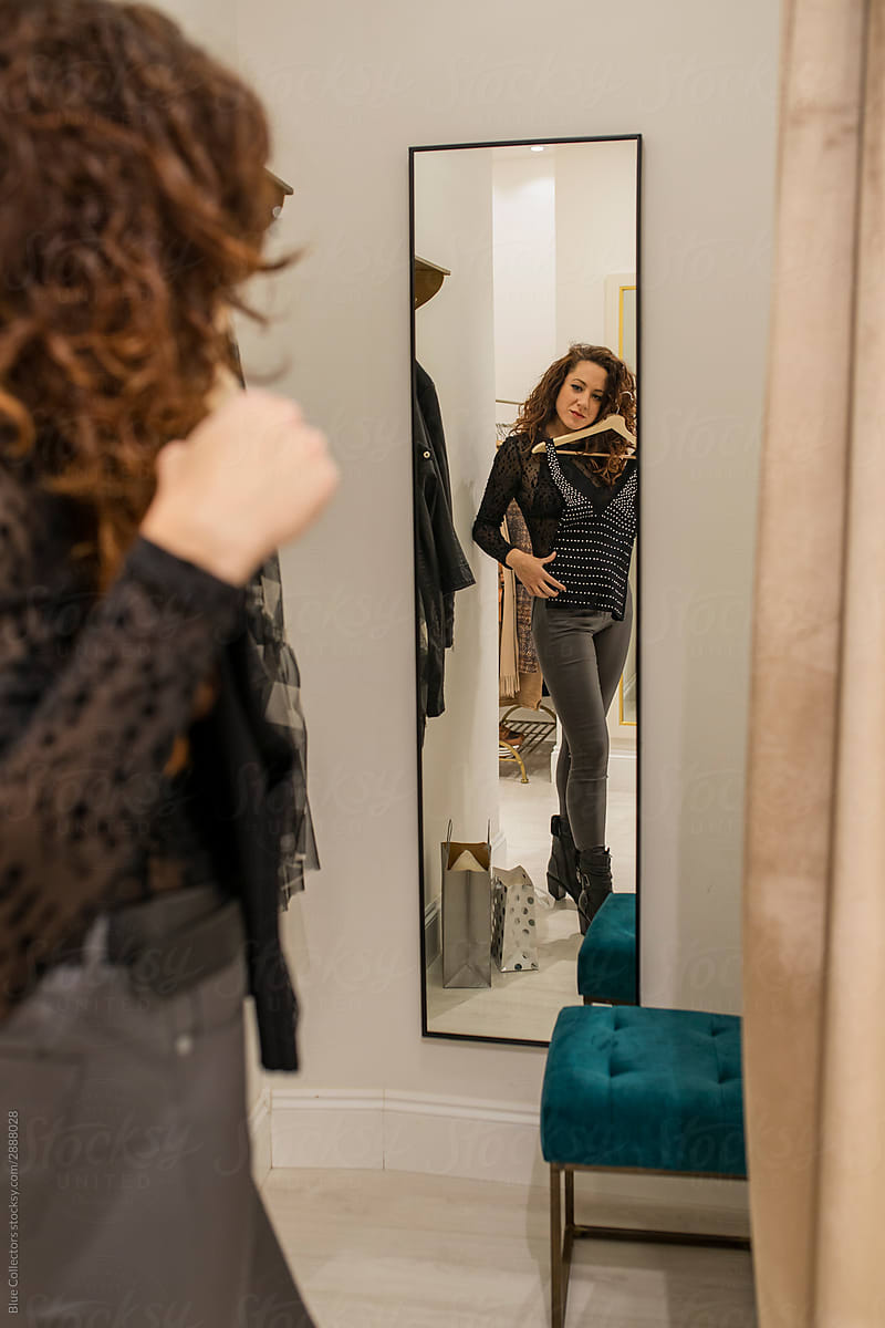 Young Woman looking at a dress in the mirror while shopping