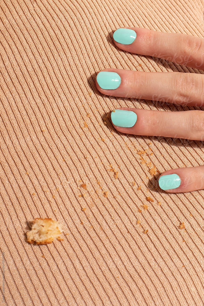 Close-up of mint/turquoise nails, beige fabric and bread crumps
