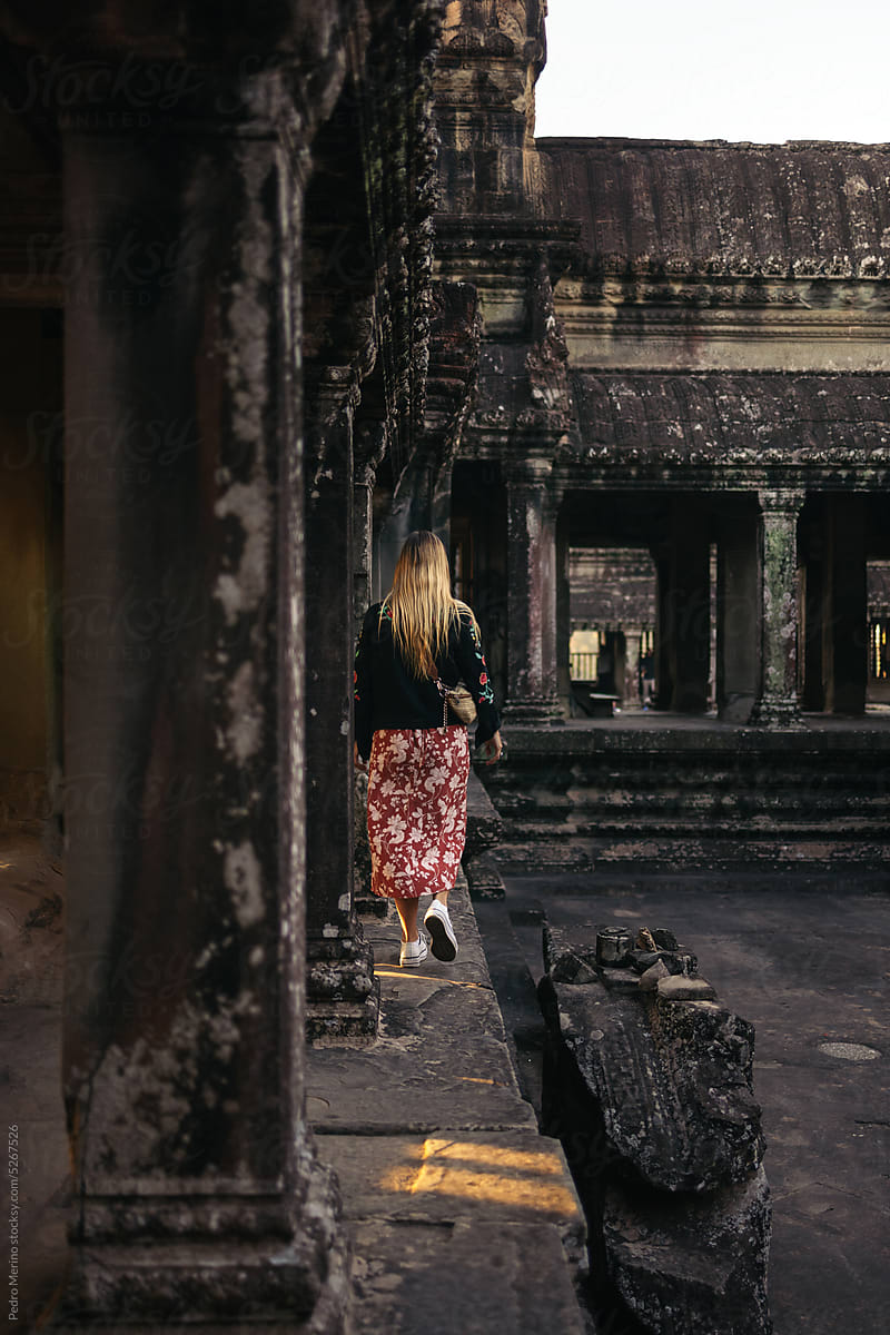 Woman walking through Angkor Wat temple ruins