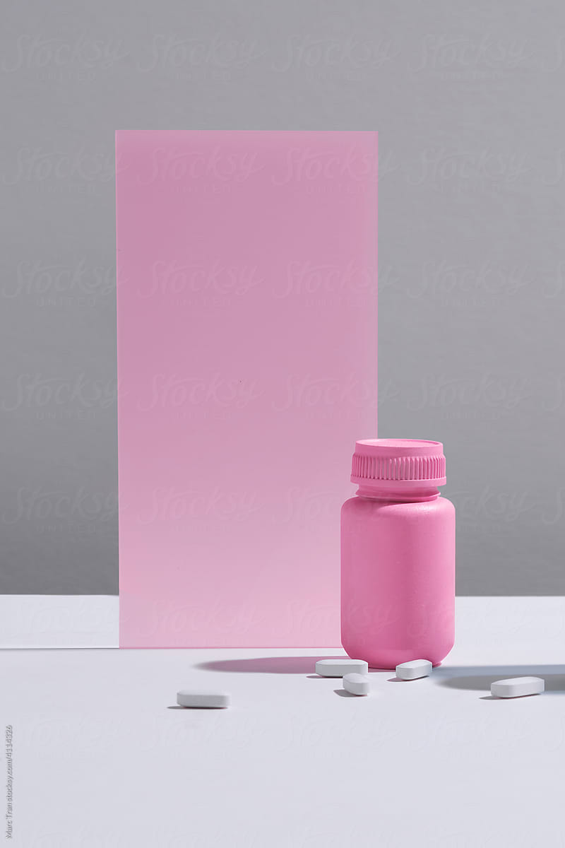 Two color medication bottles on podium against gray background