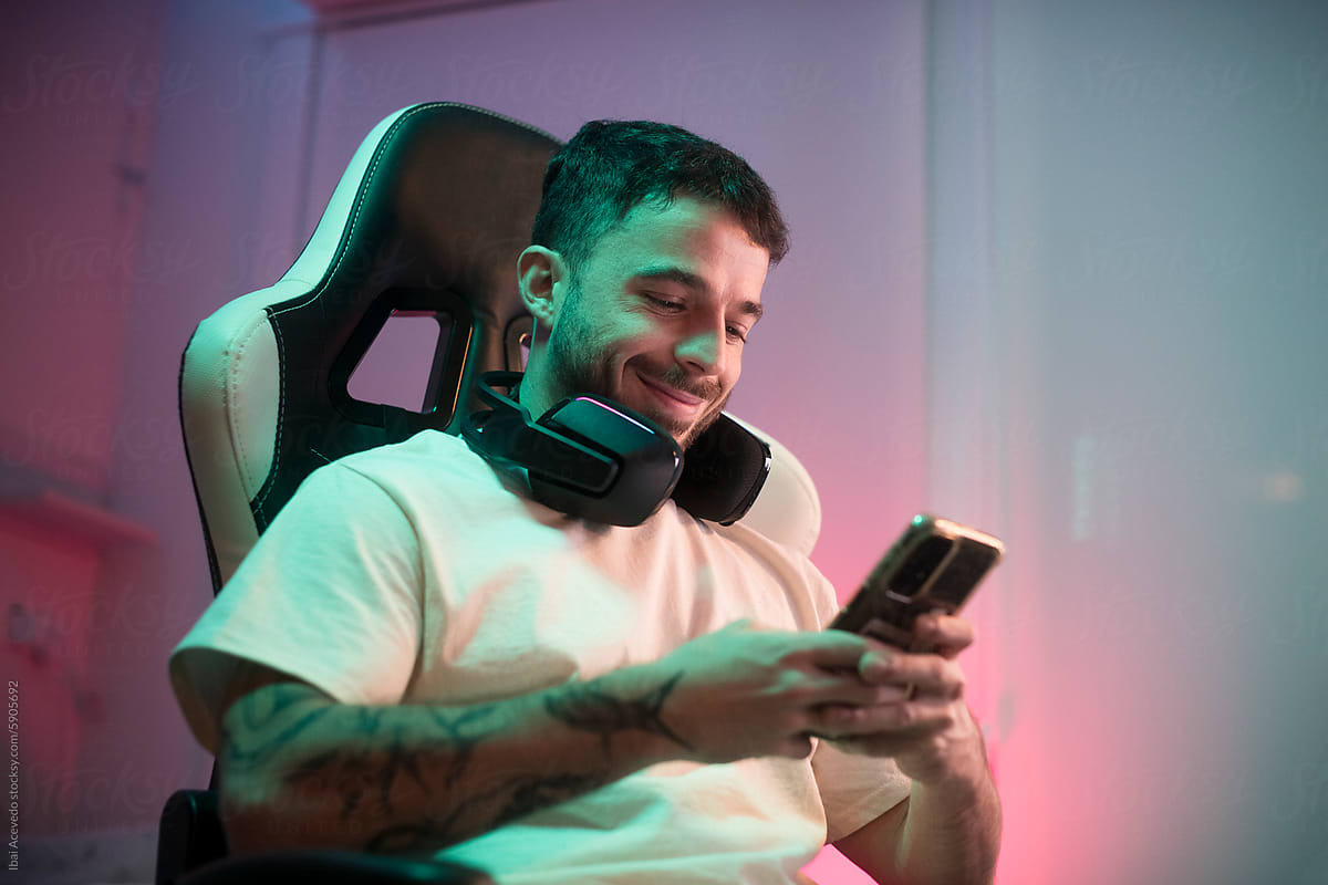 Smiling man using cellphone on video gaming chair