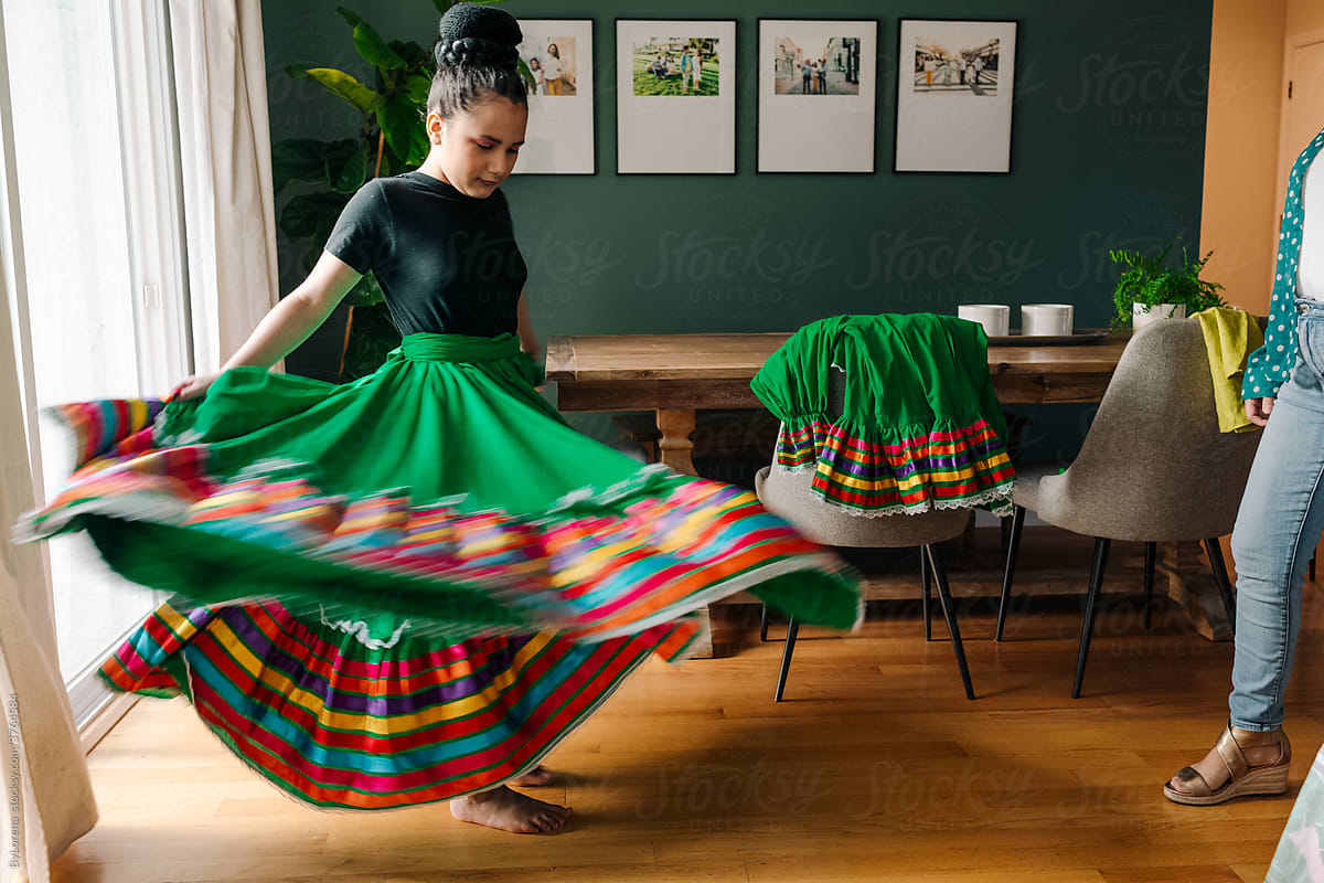 Girl dancing with colorful mexican skirt at home