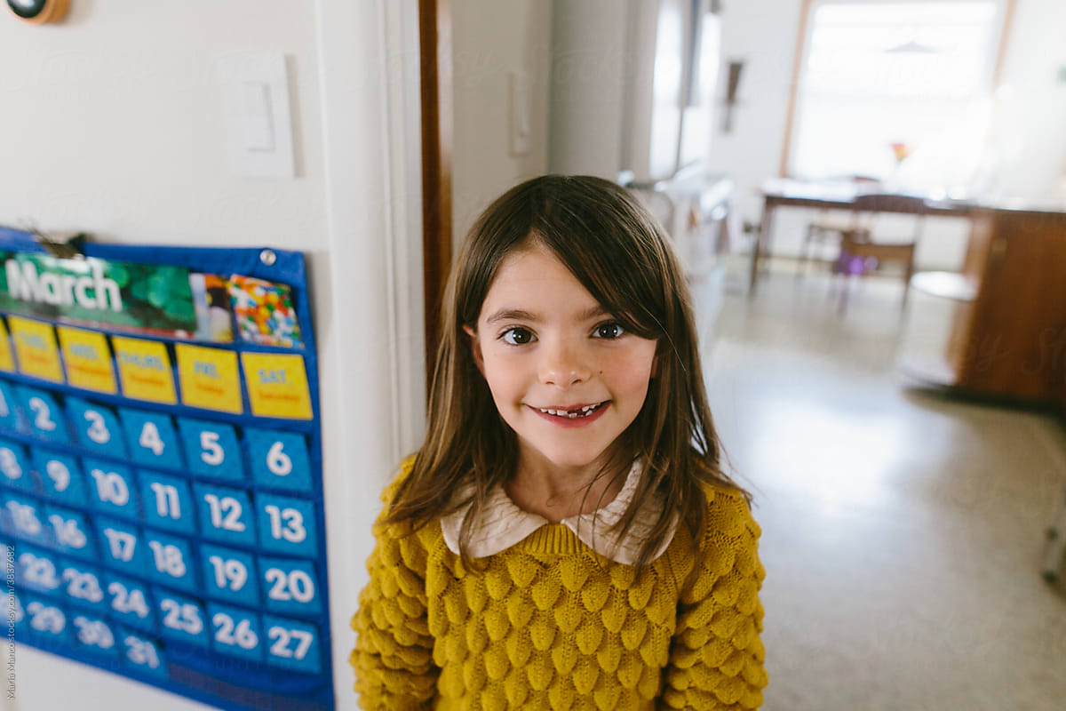 portrait of homeschooled gap-toothed school age girl in front of calendar