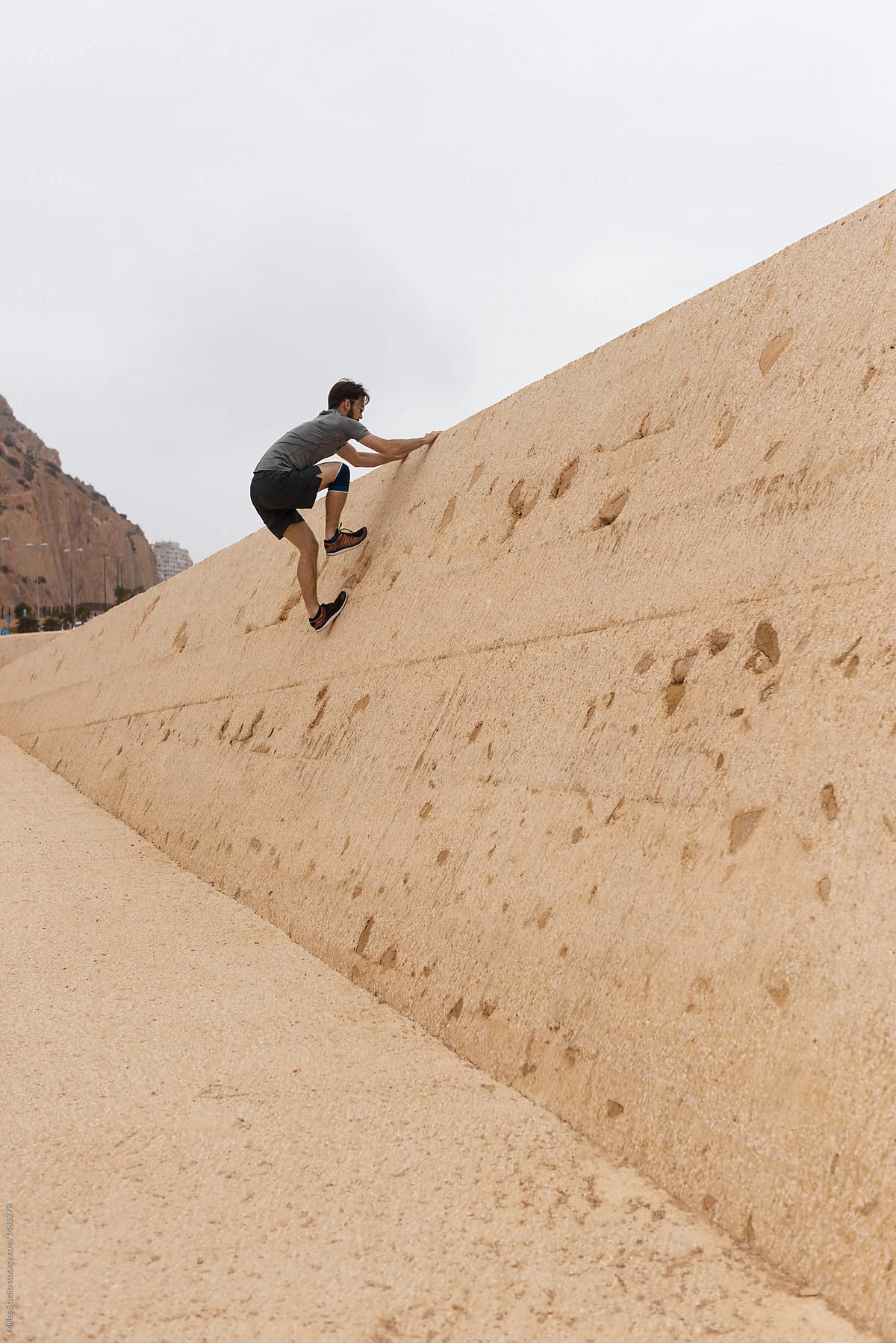 Man climbing on sandy wall