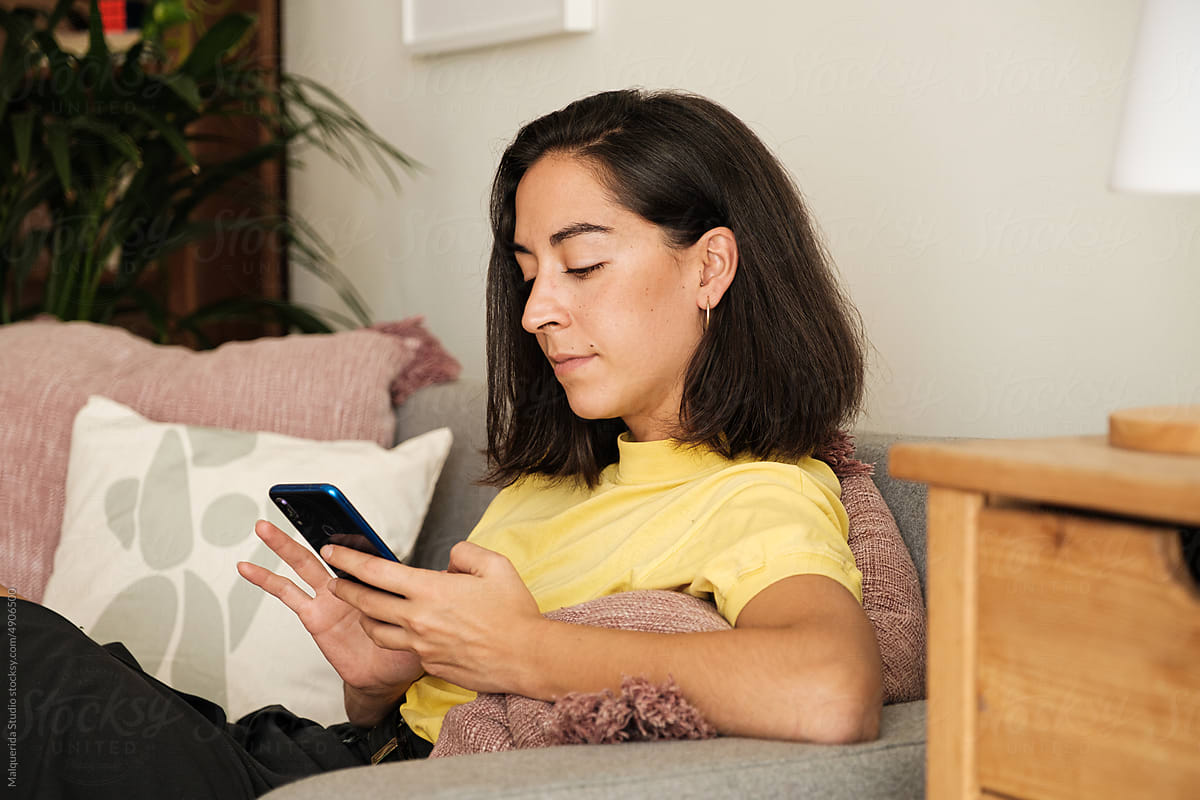 Woman using phone sitting on sofa