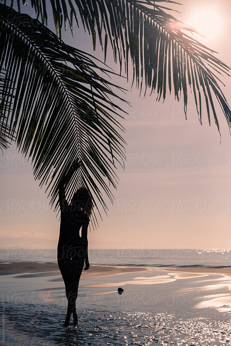 Woman walking along the beach at sunset