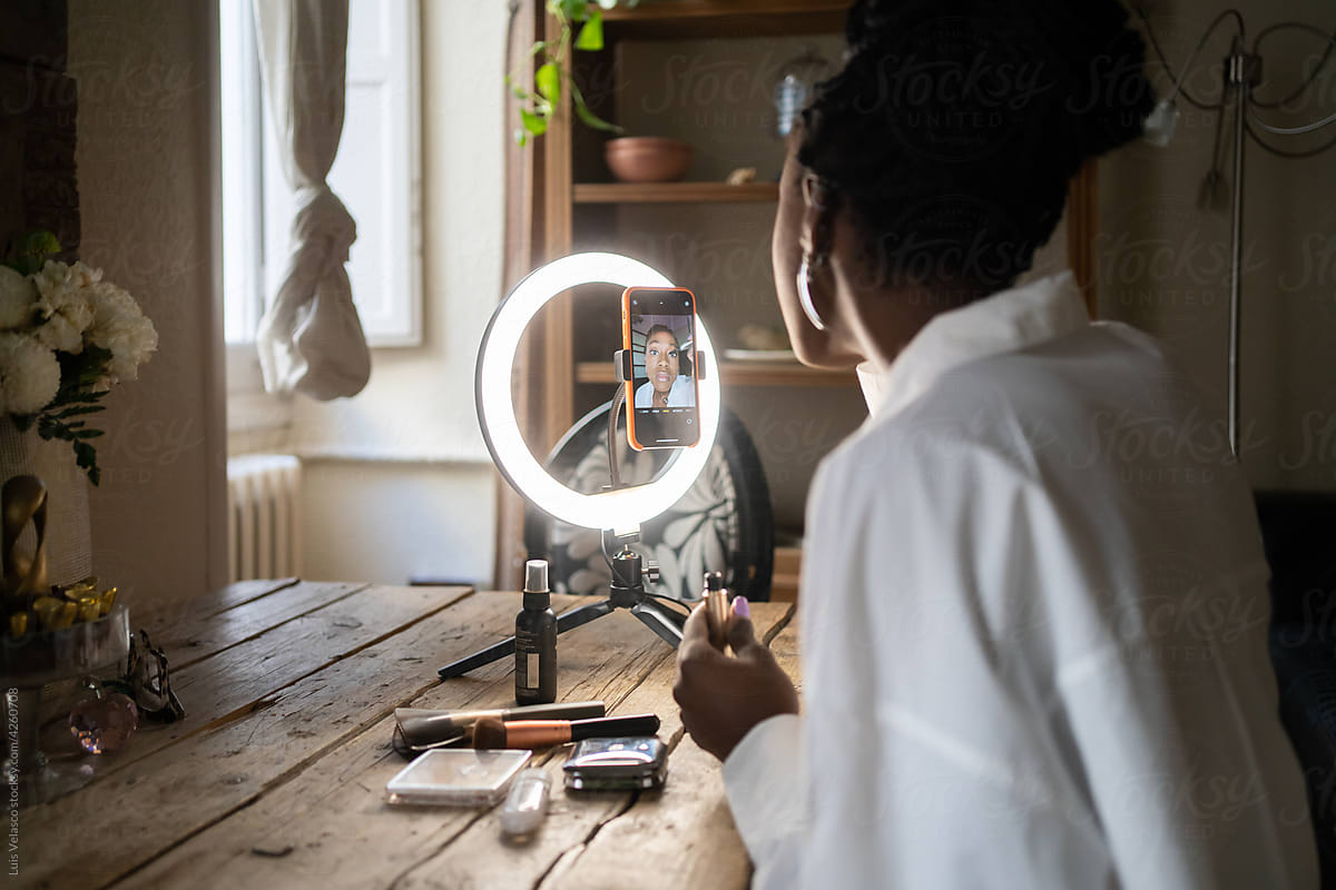 Black Woman Making Up Using Mascara In Front Of A Ring Light.