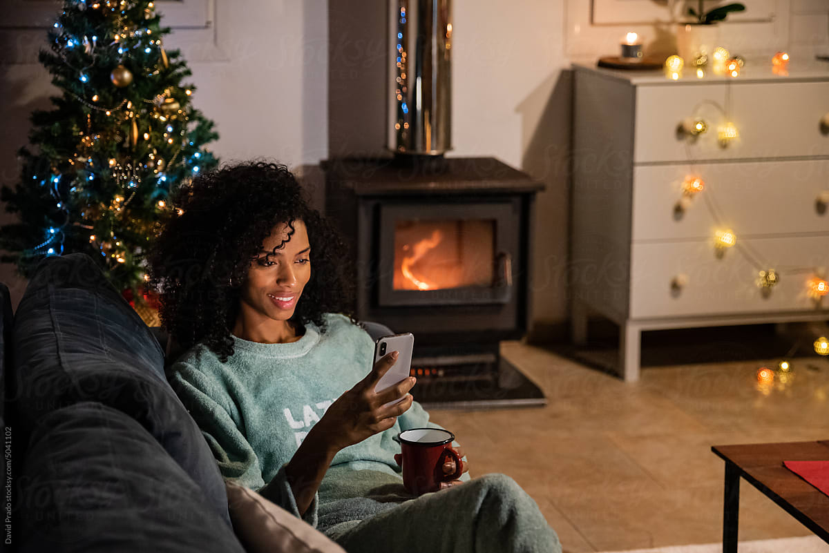 Black woman using smartphone on sofa