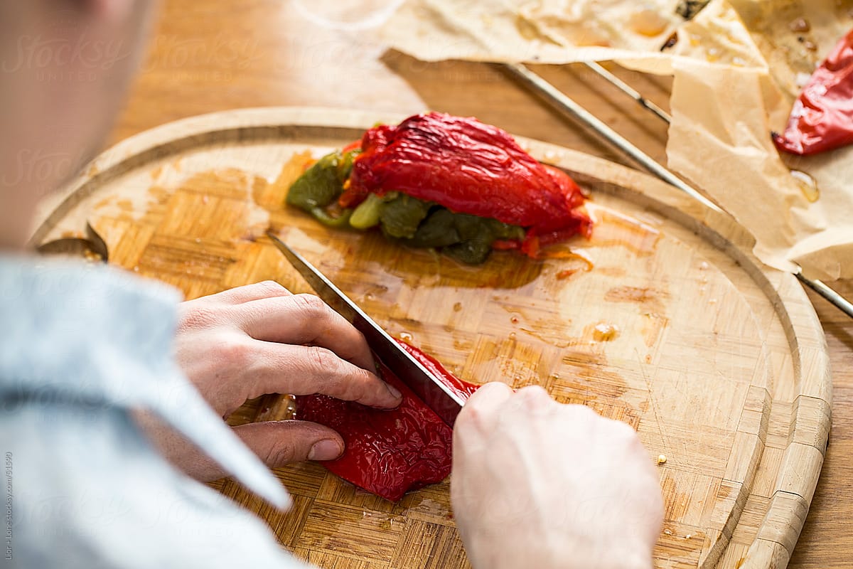 Man slicing roasted peppers on cutting board