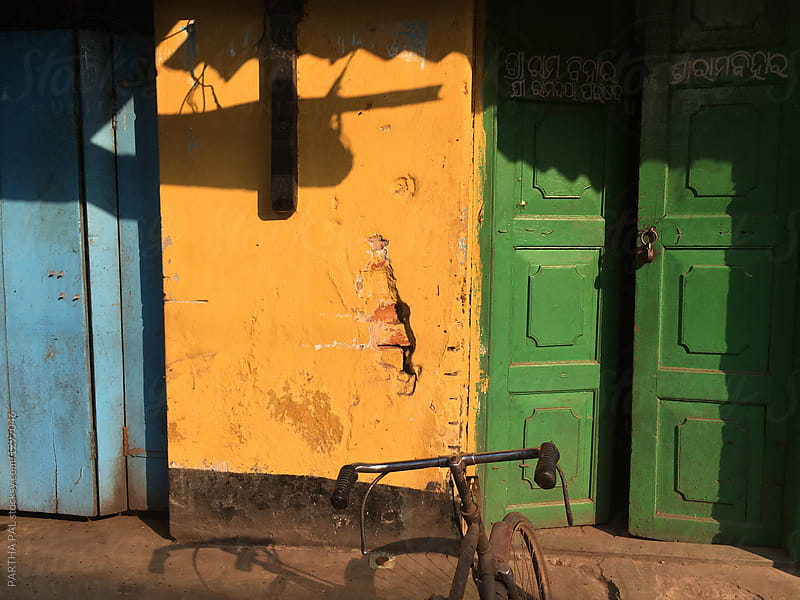 Yellow wall,green door and cycle in front of a residential house