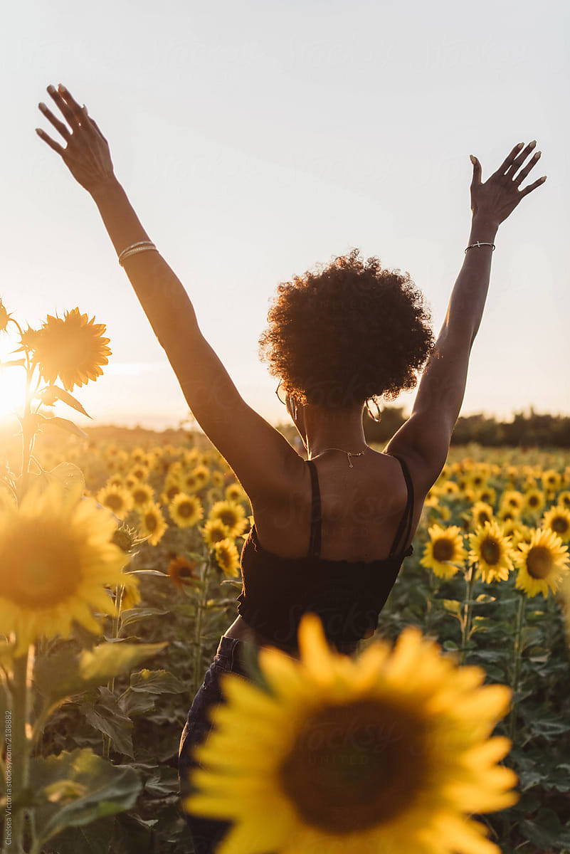 A young african american woman in a sunflower field at sunset