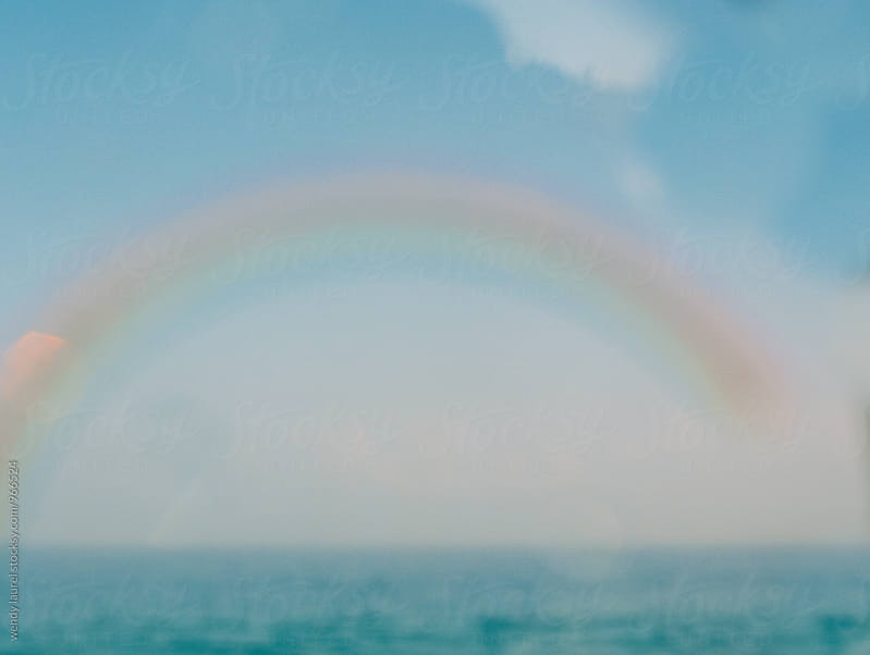 rainbow over ocean with blue water and sky
