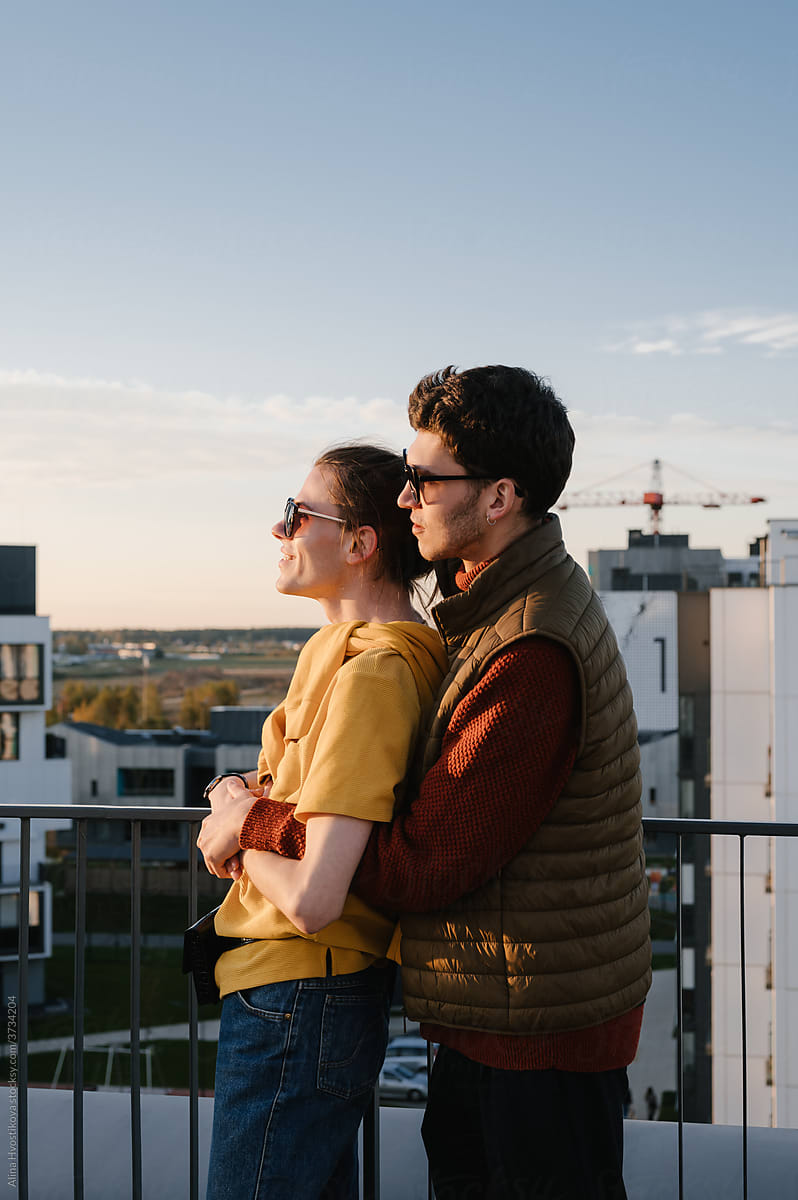 Gay couple resting on balcony at sunset
