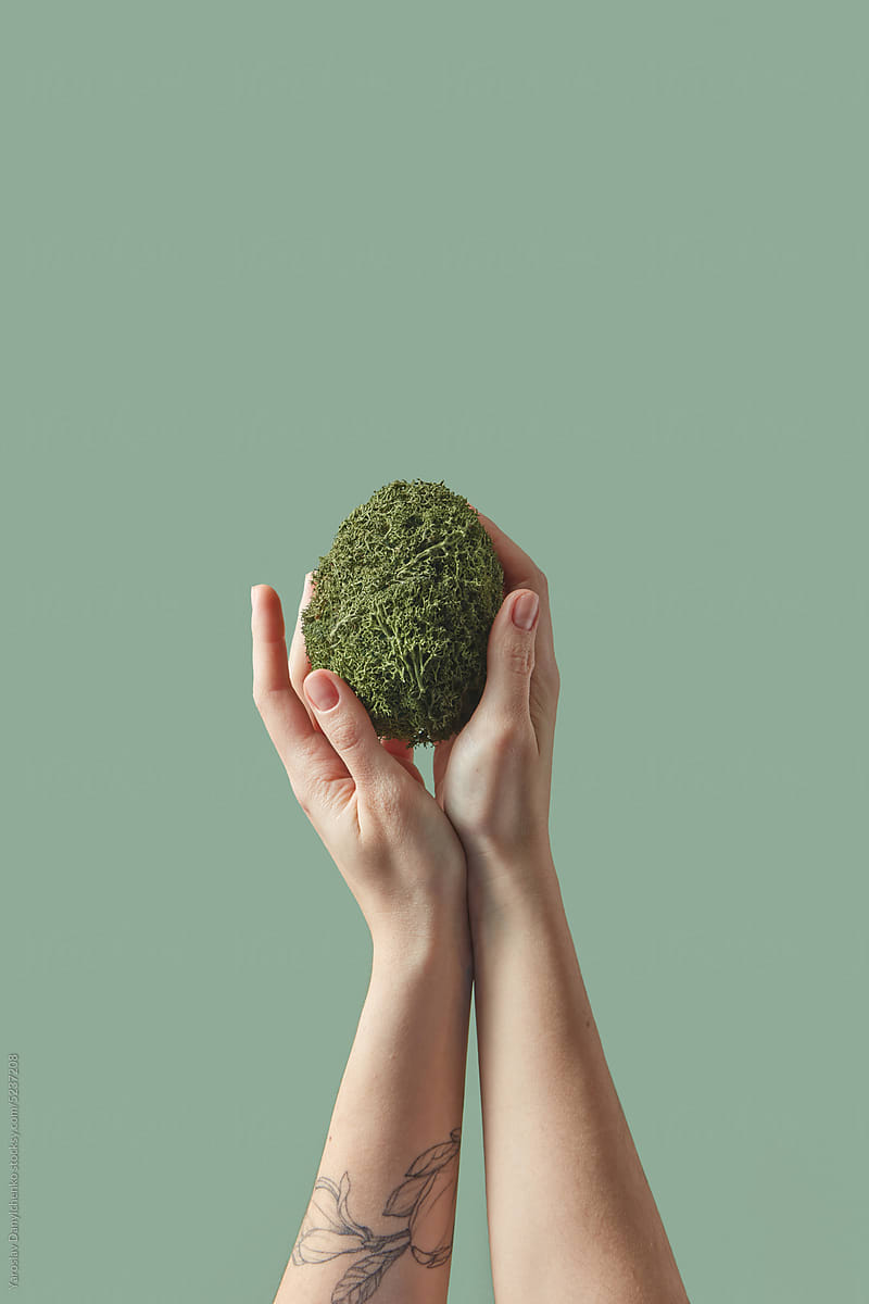 Crafted green Easter egg held by woman\'s hands.