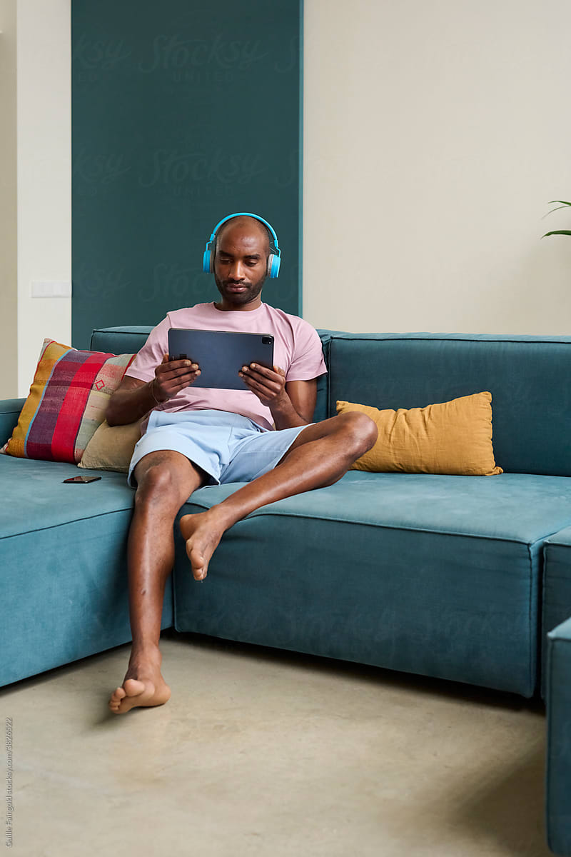 Black man with tablet in hands and headphones.