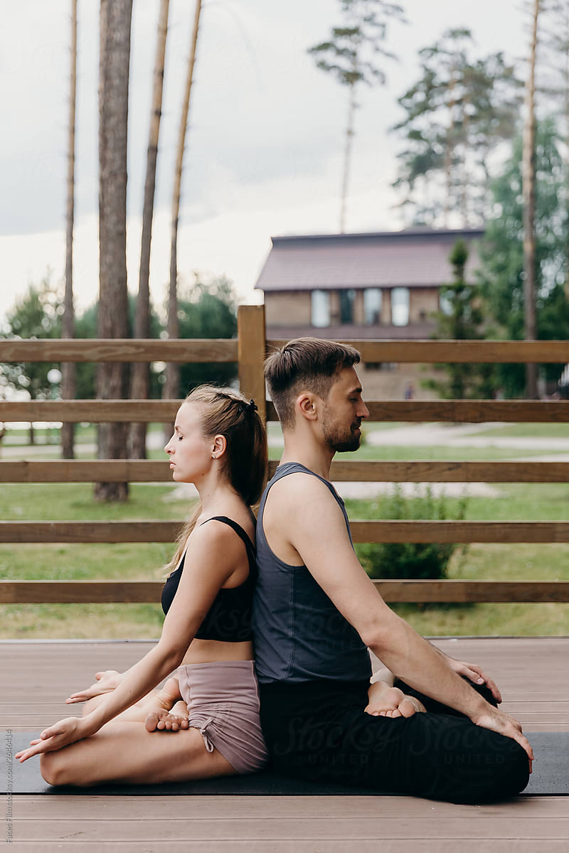 Pair yoga outside on a nature. Man and woman sitting together back to each other in lotus pose.
