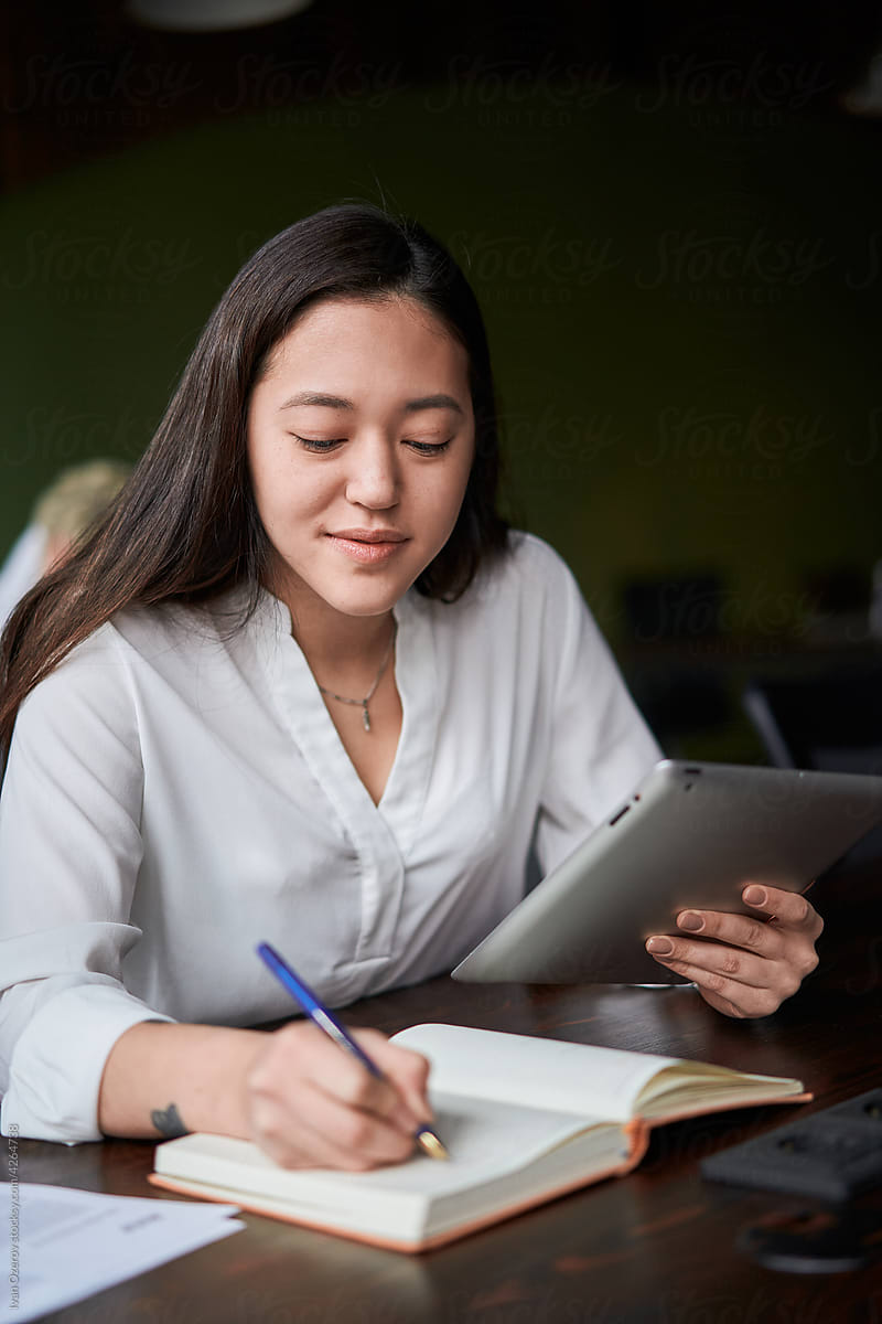 Asian employee making notes from tablet
