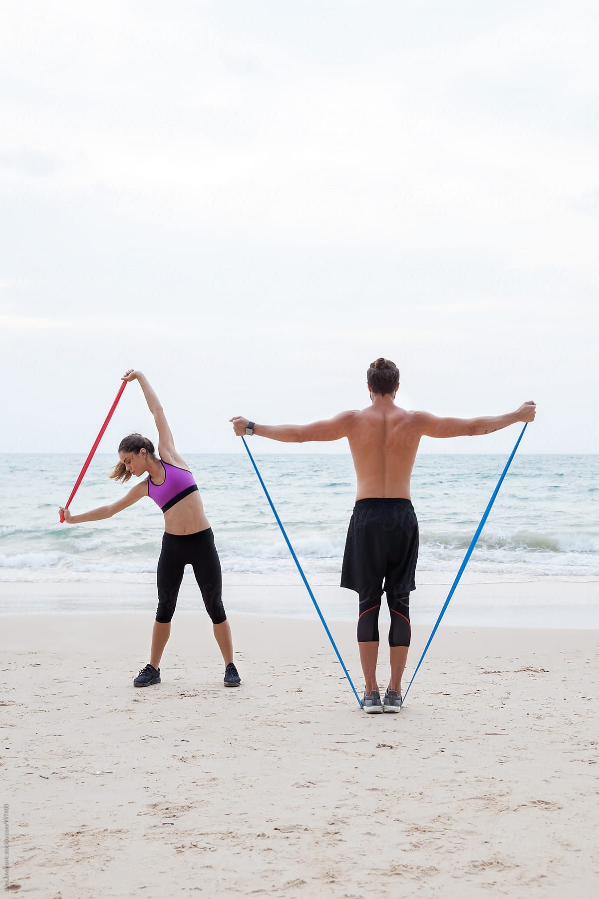 Fitness, sport, friendship and lifestyle concept - couple exercising at the beach