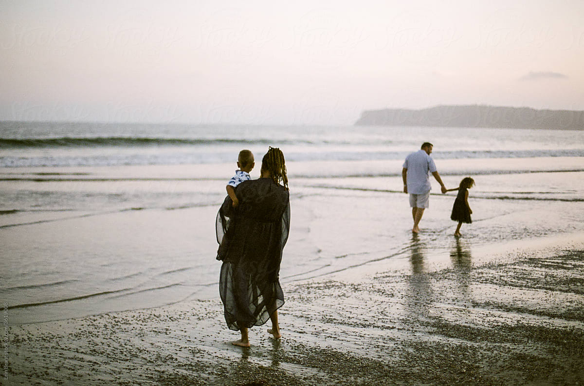 Family wading in ocean at sunset
