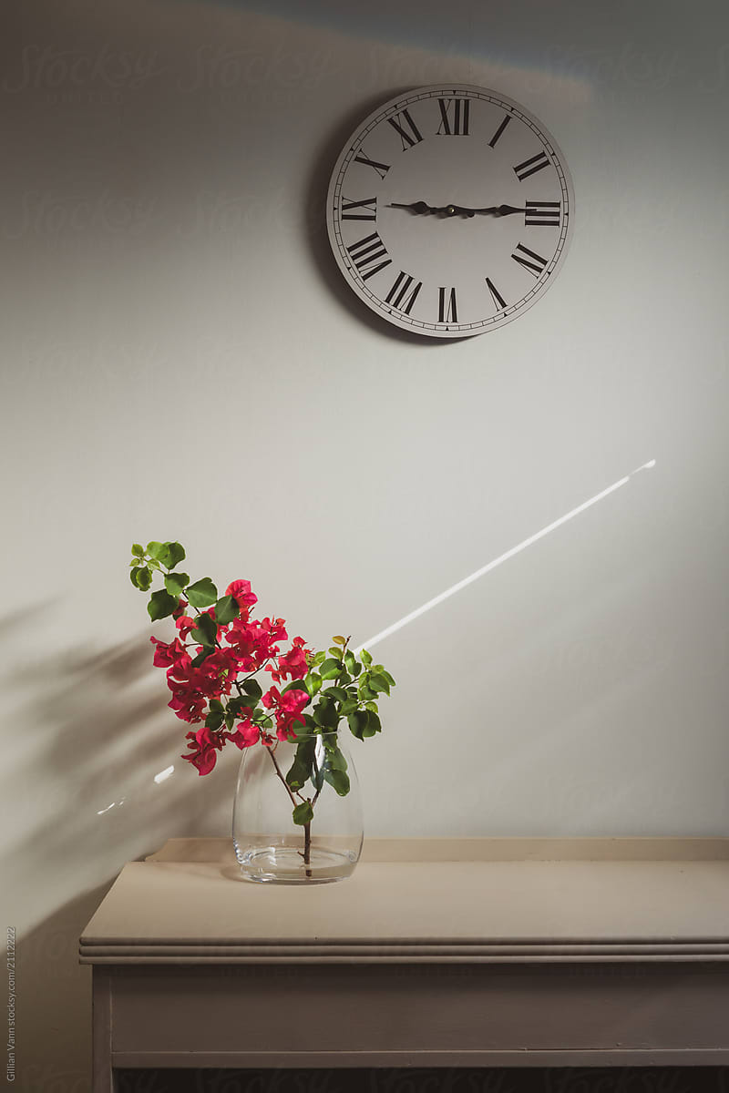 interior decor, glass vase with pink flowers and clock