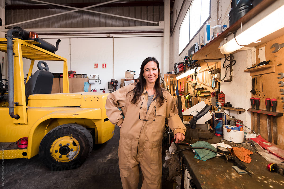 Happy female mechanic standing at workshop