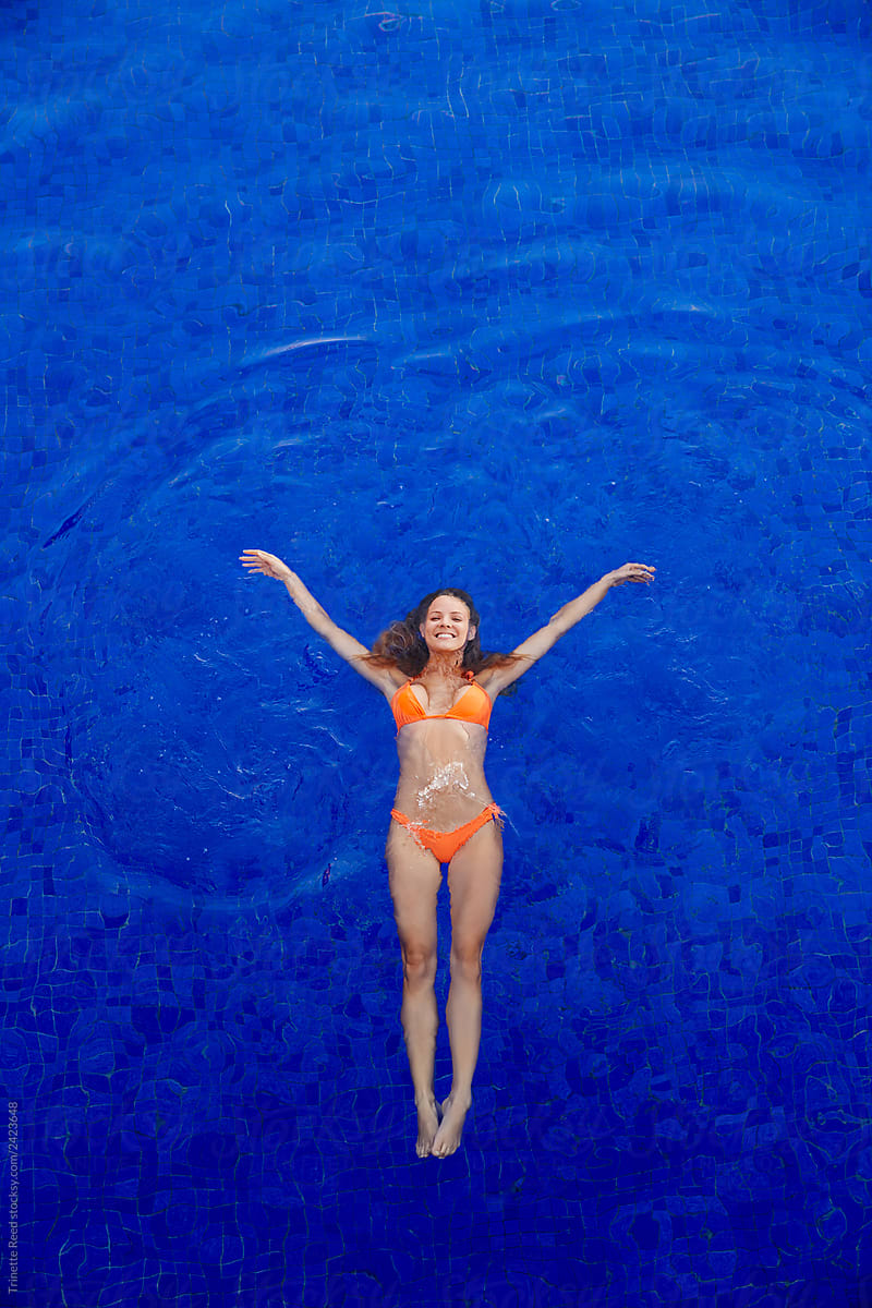 Overhead view of woman floating in water in a blue pool