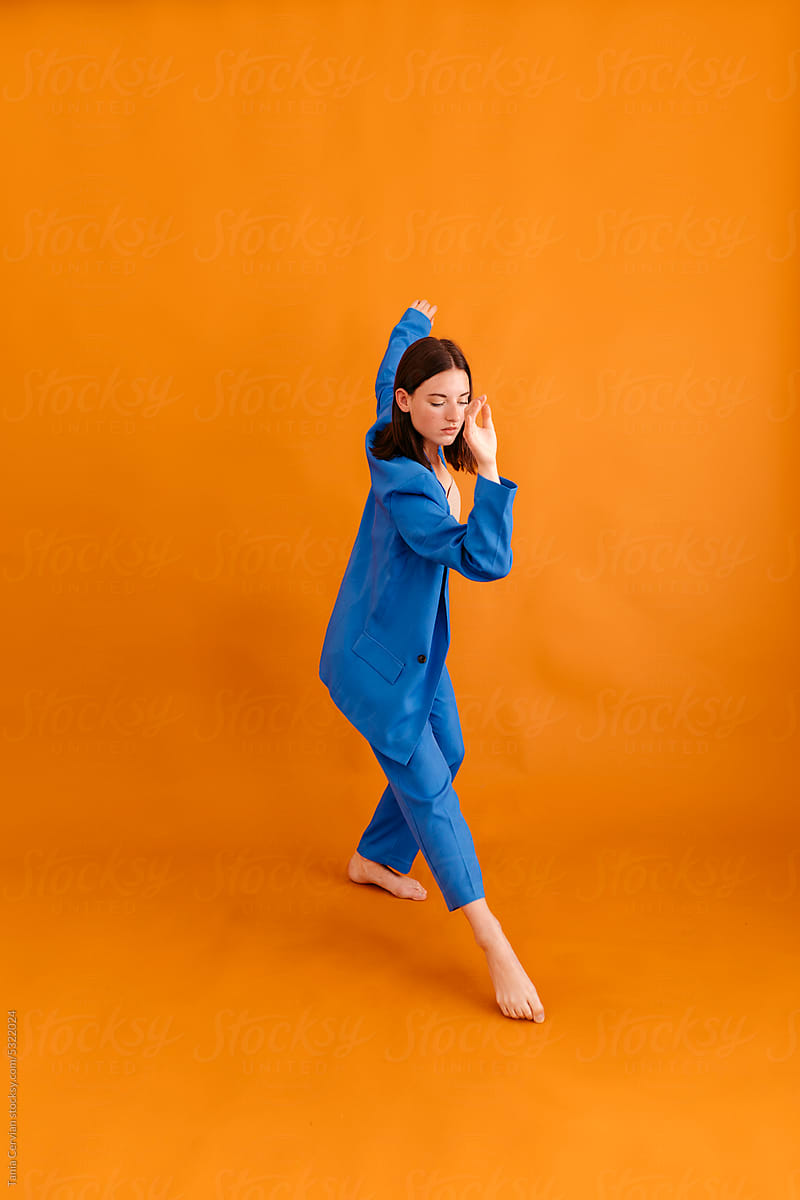 Young woman standing in dance pose on orange floor