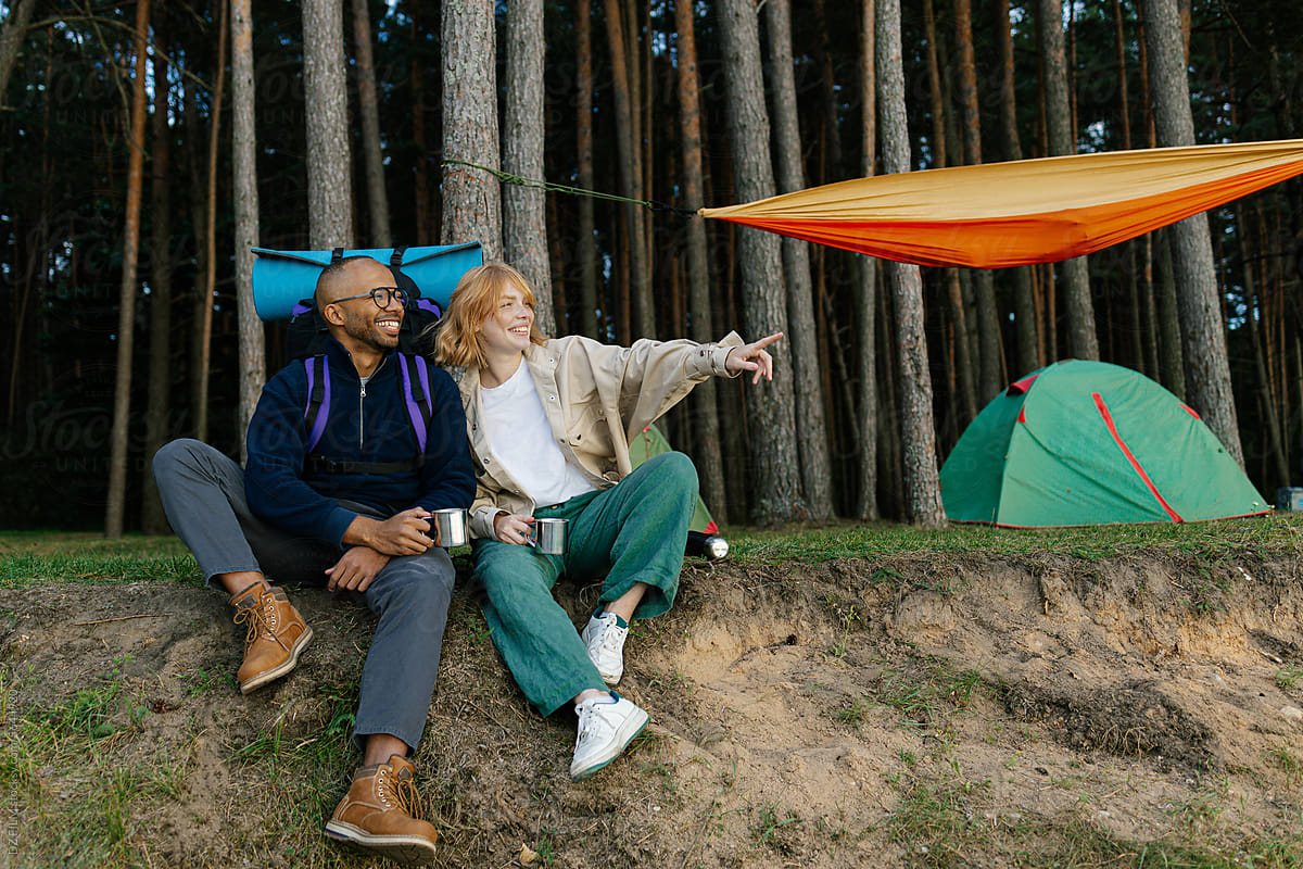 A man and a woman drink tea at a camping