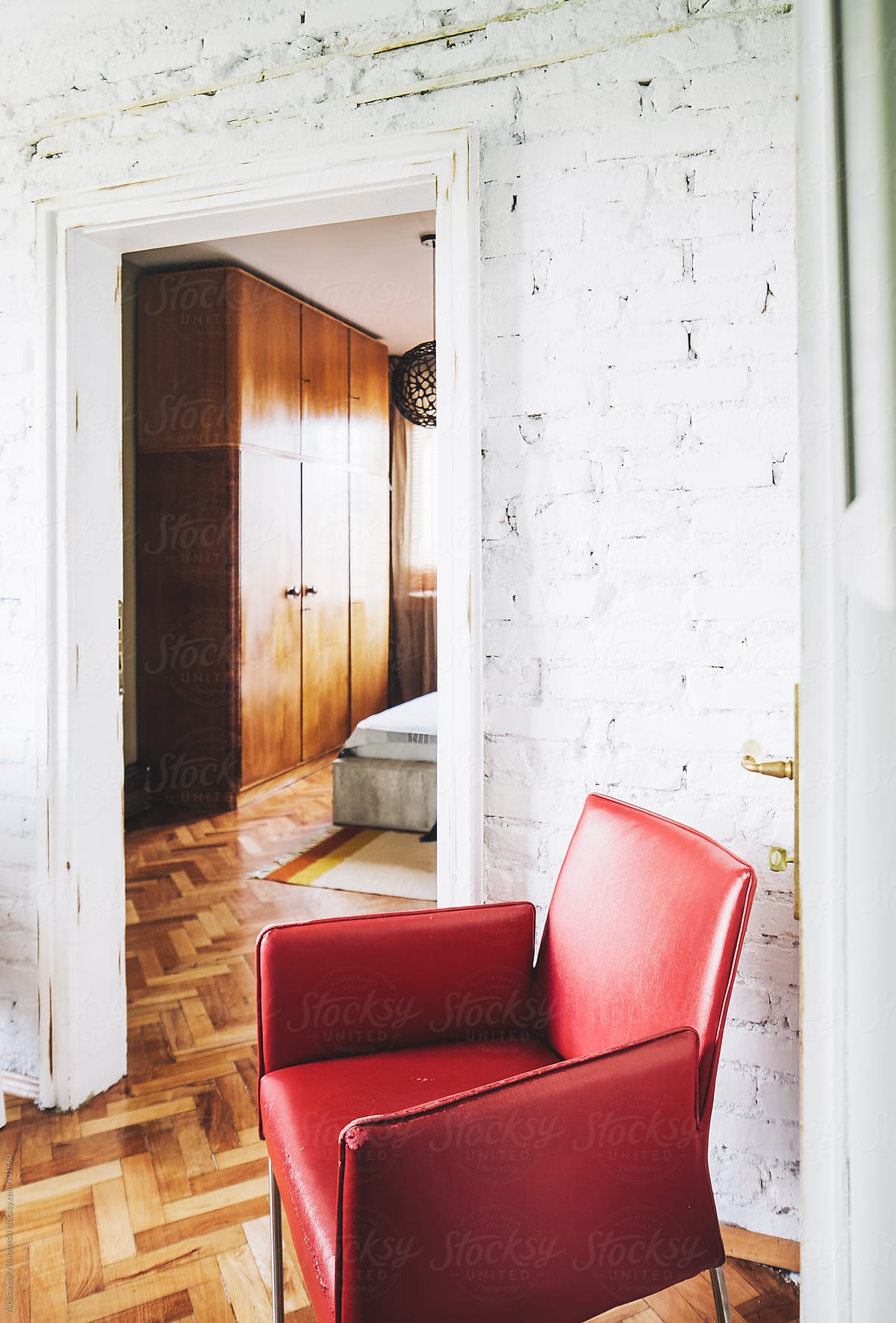 Red armchair and entry to bedroom in cosy interior