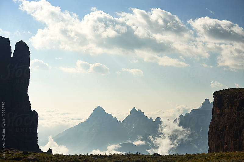 A beautiful mountain landscape with sharp spiking peeks and clouds.