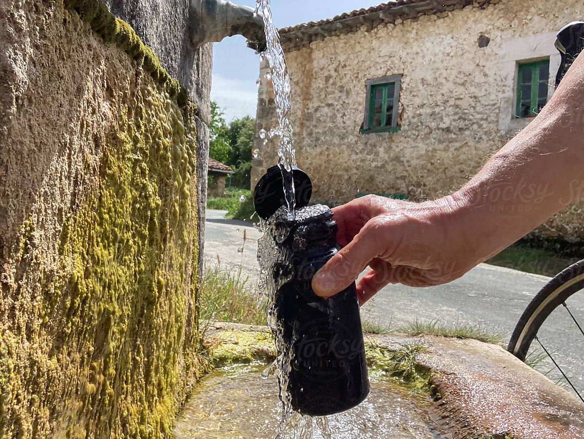filling a water bottle at an old village fountain in rural Spain
