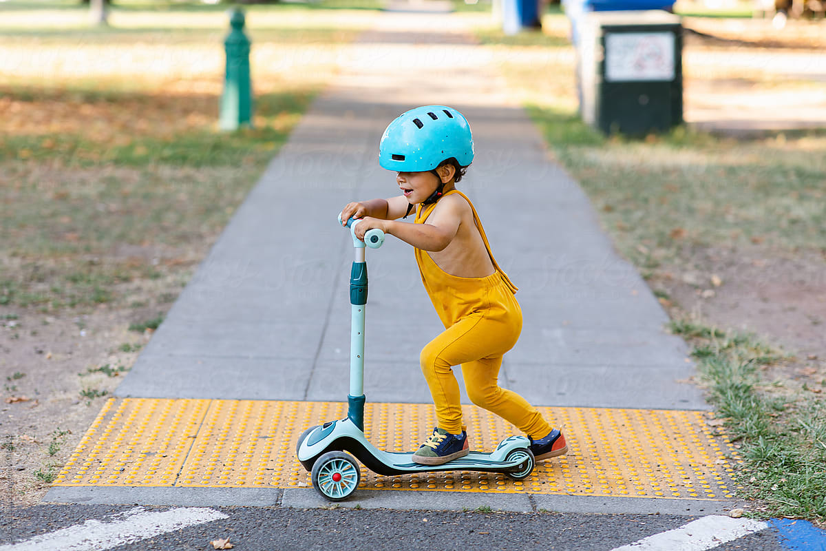 Toddler riding kick scooter on asphalt