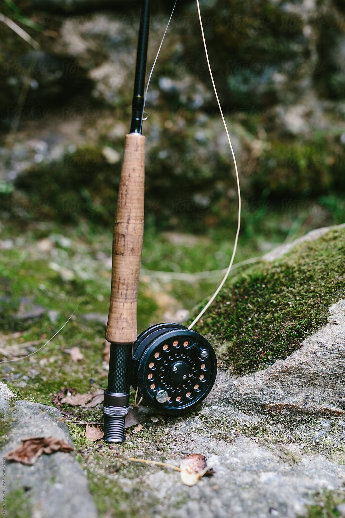 Fishing rod and reel on rocky riverbank ready to catch fish