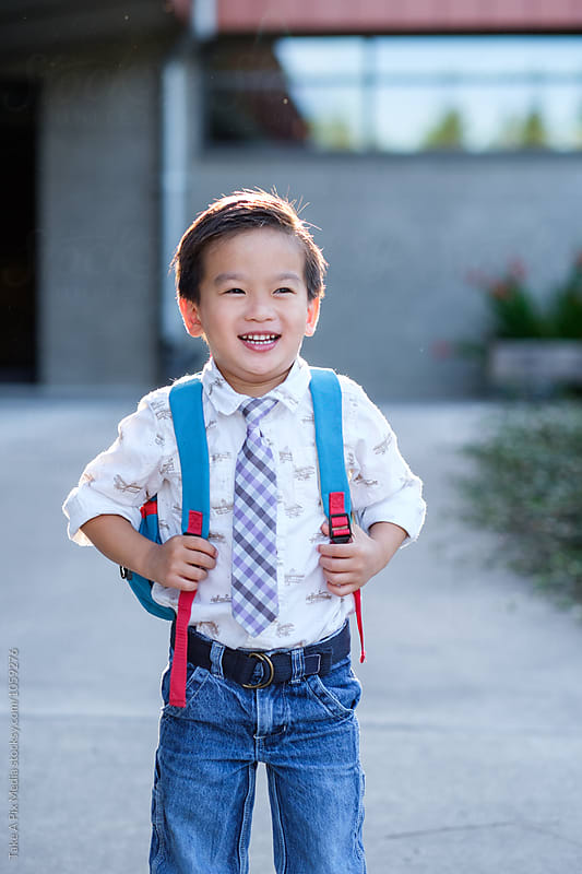 Back to school: Happy Asian kid carrying a backpack in school