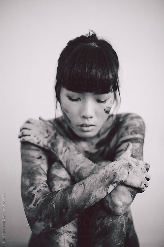 Black and white portrait photo of young beautiful Asian woman with messy paint on the body
