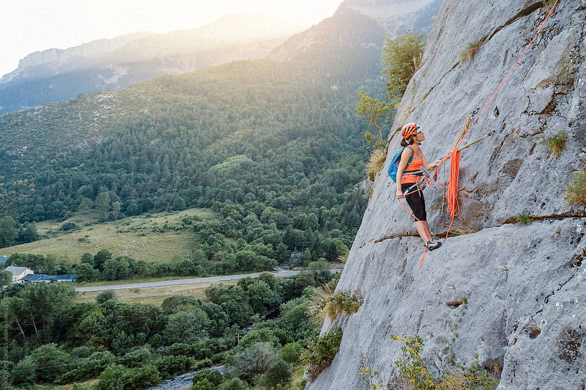 Young woman climbing a big rock wall.