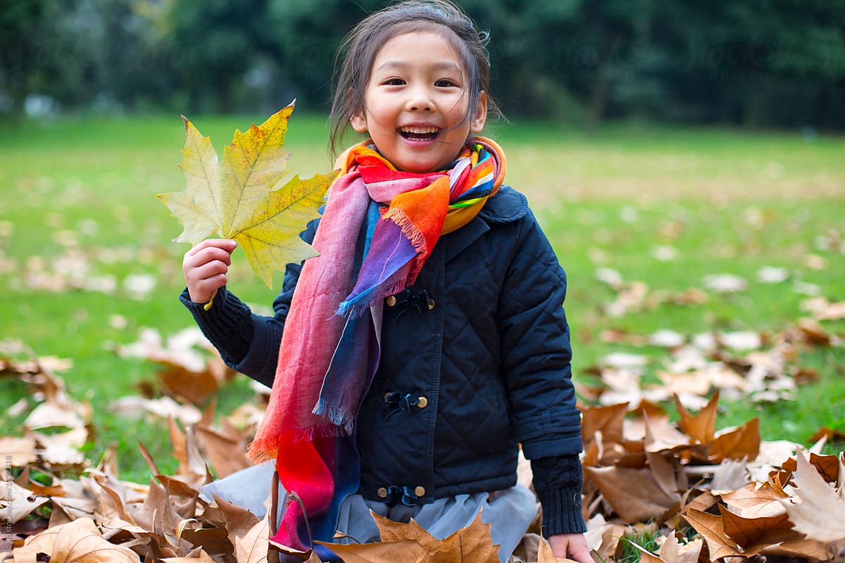 Lovely Little Girl Playing with Leaf outdoor in the Autumn day