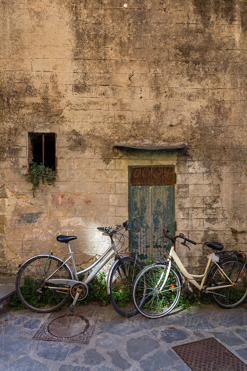 Two bicycles parked in front of an old brick wall.