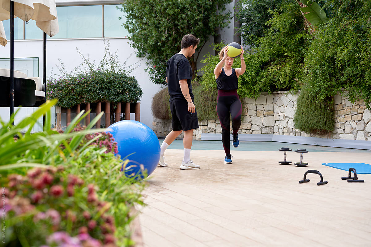 Fit woman exercising with medicine ball with trainer