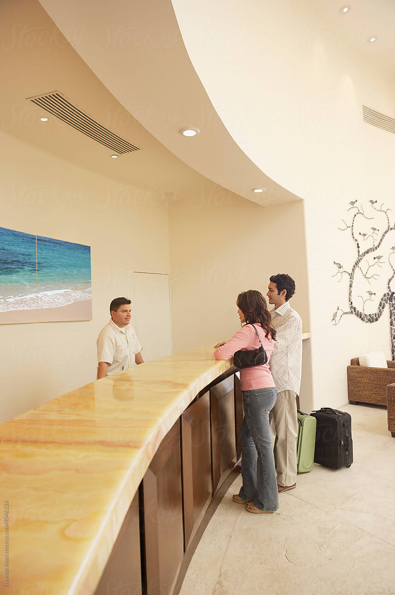 Couple checking in at luxury hotel reception front desk