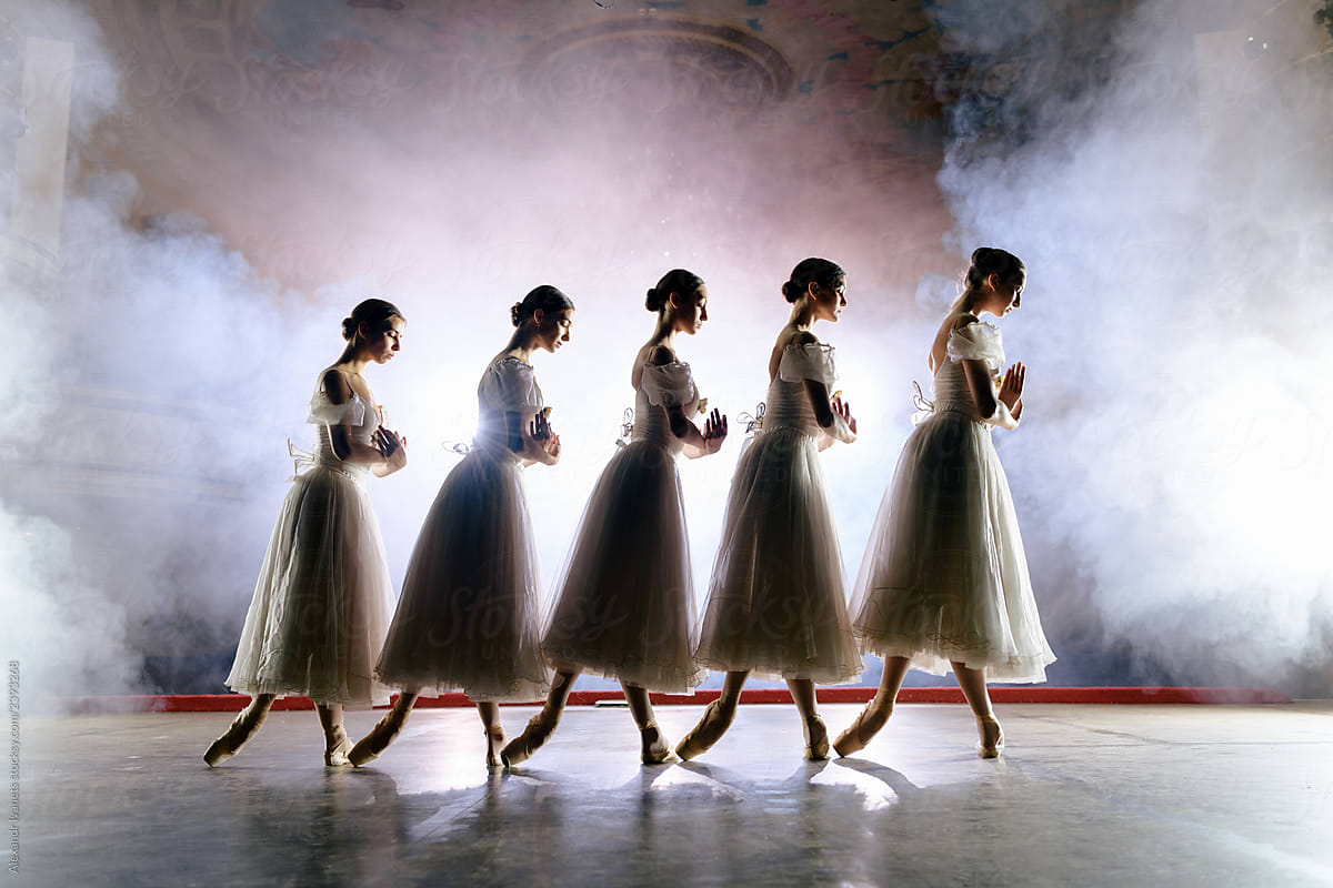 Row of ballerinas in dresses posing on scene