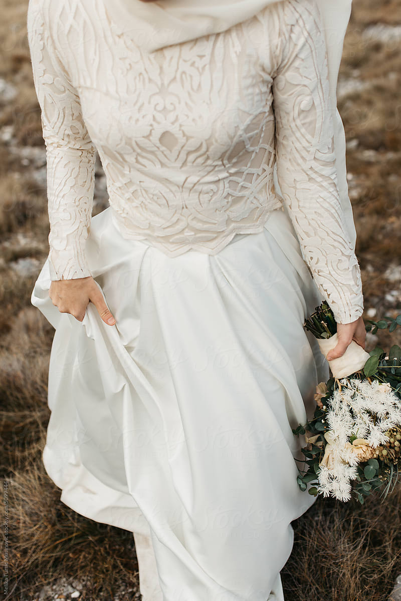Close up photo of a bride walking and holding bouquet