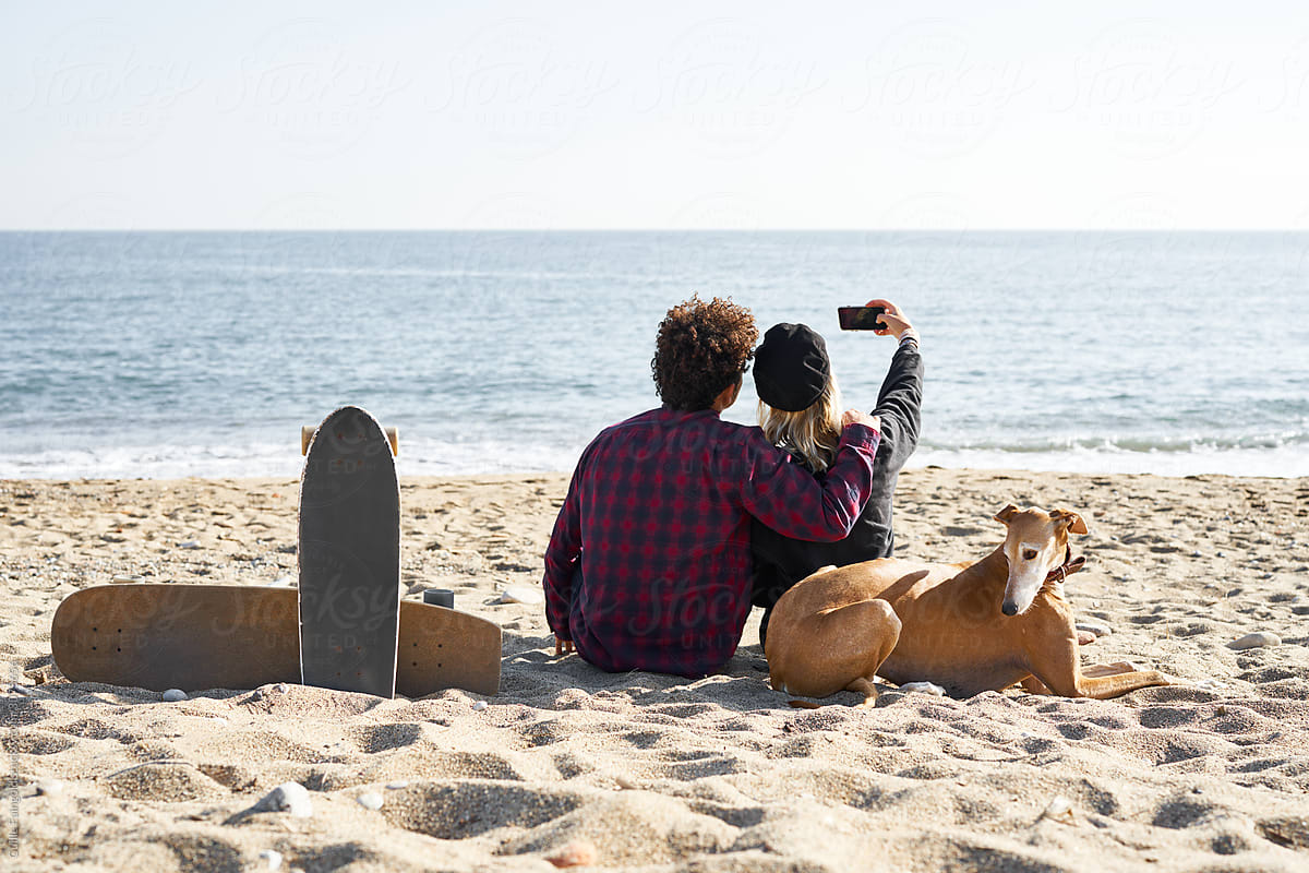Couple making selfie on mobile on beach.