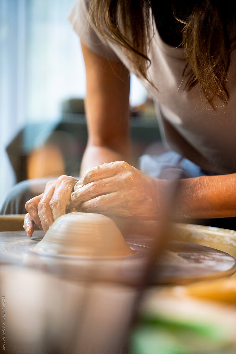 Woman\'s hands sculpting clay on pottery wheel