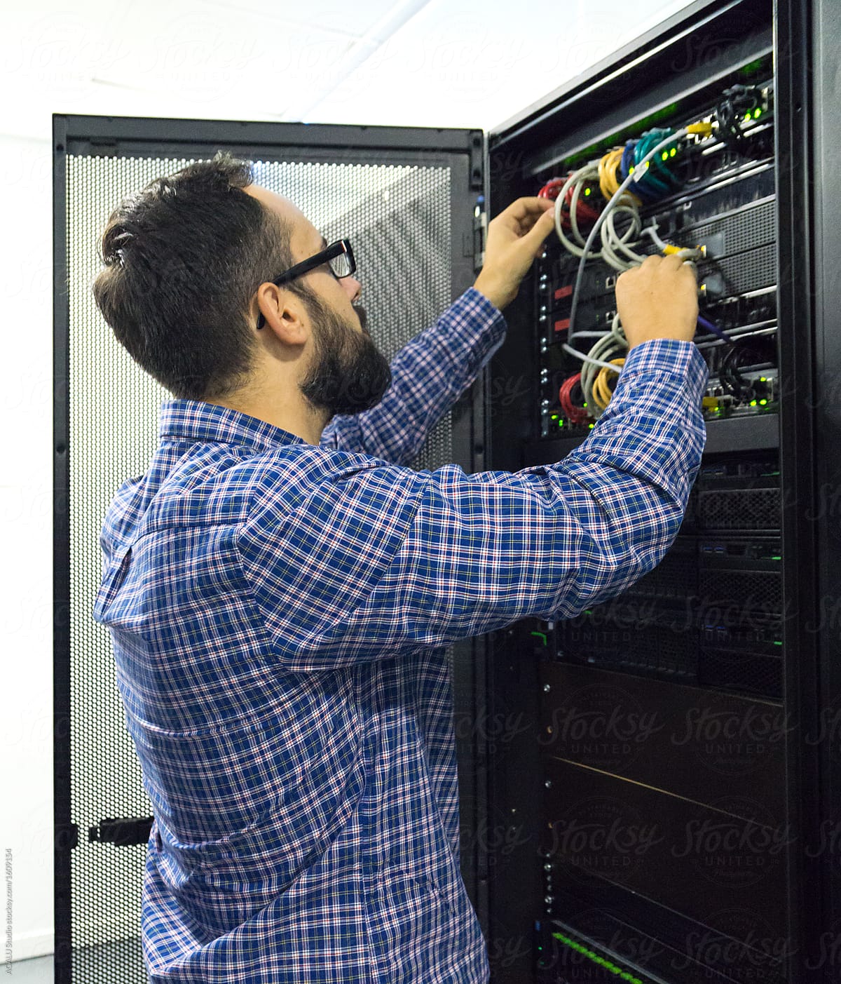 Technician performing maintenance tasks in a server room rack