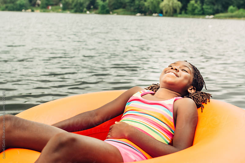 Black girl relaxing on an orange inner tube